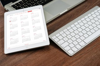Calendar, Apple Laptop, Apple keyboard, wooden desk.